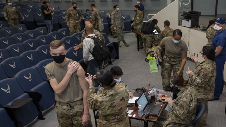 Image of Military personnel wearing face mask standing in line to receive their COVID-19 Vaccine.