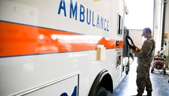 Military personnel inspect an ambulance