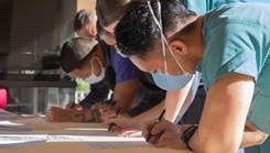 Sailors wearing masks, leaning on a table and writing on sheets of paper