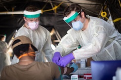 Hospital Corpsman 2nd Class Shane Miller, left, and Hospital Corpsman 2nd Class Austin Kelly, both assigned to Fleet Surgical Team 9, draw blood from a Sailor assigned to the guided-missile destroyer USS Kidd (DDG 100) after its arrival in San Diego April 28 as part of the Navy’s aggressive response to the COVID-19 outbreak on board the ship. While in San Diego, the Navy will provide medical care for the crew and clean and disinfect the ship. (U.S. Navy photo by Mass Communication Specialist 2nd Class Alex Corona/ Released)