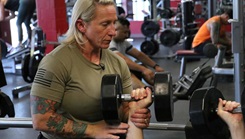 A woman helps a person lifting weights