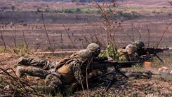 Military personnel crouched on the ground 