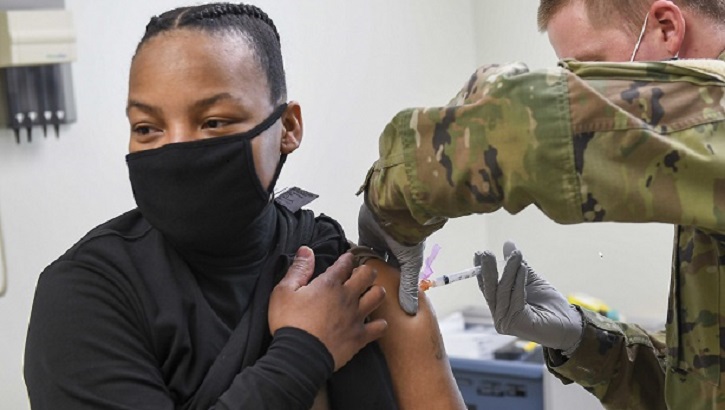 Image of Military personnel wearing a face mask receiving the COVID-19 vaccine.