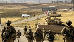 Soldiers patrol in Syria in front of a Bradley tank.