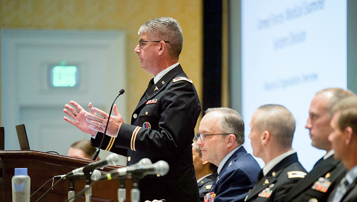 Image of Military personnel speaking in front of an audience at the Military Health Systems Research Symposium.
