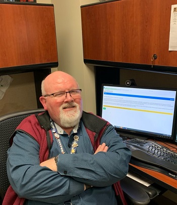 Rick Barnhill sitting in front of a screen with all the COVID-19 vaccination appointments scheduled