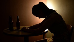 Shadowed image of person sitting at a desk with their head down