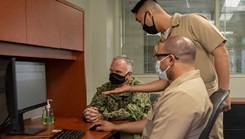 Image of three military personnel, wearing masks, in front of a computer screen. Click to open a larger version of the image.