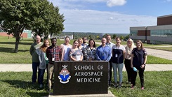 Military personnel posing by Wright-Patterson AFB sign