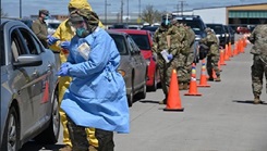 Military personnel performing nasal swabs of people in a row of cars