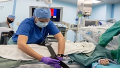 Military health personnel securing a patient to the operating table