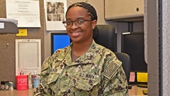 Military personnel sitting in cubicle and smiling