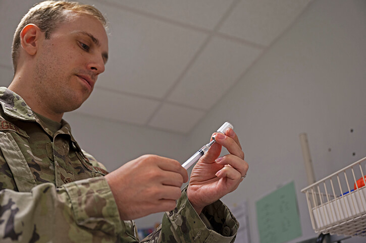 Air Force Staff. Sgt. fills a syringe with a COVID-19 vaccine at Ramstein Air Base, Germany.