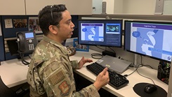 A service member watches a computer screen.