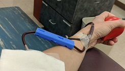 Person's hand and arm, squeezing a ball, giving blood