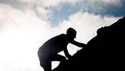 Silhouette of man climbing a hill