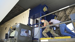 Soldiers in masks pushing a piece of equipment