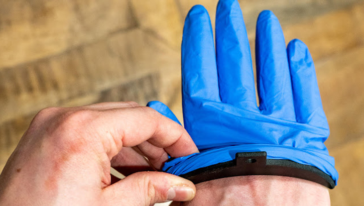 Medical students at Uniformed Services University invented the crescent -shaped device to keep several layers of nitrile gloves open. This allows a health care provider to insert their hand and have multiple layers on in a few seconds. (Courtesy Photos/U.S. Air Force)
