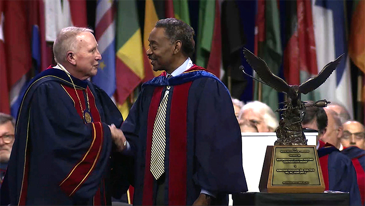 American College of Surgeons President Dr. E. Christopher Ellison presents the ACS Distinguished Lifetime Military Contribution Award to USU President Dr. Jonathan Woodson on Oct. 22, 2023.  (Screenshot photo captured by Cathy Hemelt, USU)