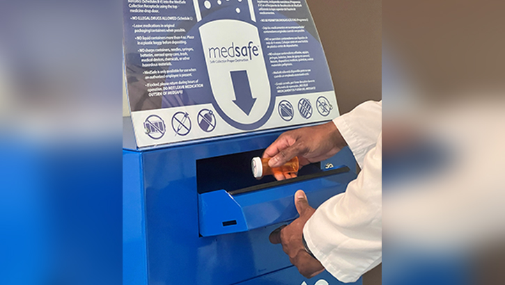 U.S. Navy Lt. Cmdr. Ramon Paul, service chief of Walter Reed National Military Medical Center Ambulatory Procedure Unit, demonstrates how easy it is to safely dispose of unused or expired prescriptions using one of two MedSafe collection bins at WRNMMC. 