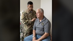 Maj. (Dr.) Avinash Chaurasia, radiation oncologist, examines Scott Anglin at Brooke Army Medical Center, Joint Base San Antonio-Fort Sam Houston